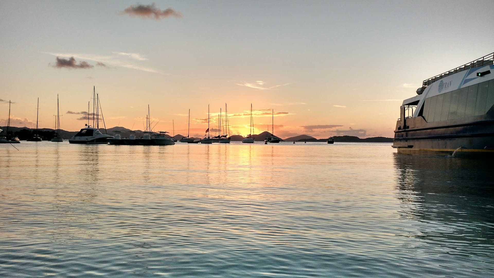 Ferry arriving in Cruz Bay at sunset with boats anchored in the harbor