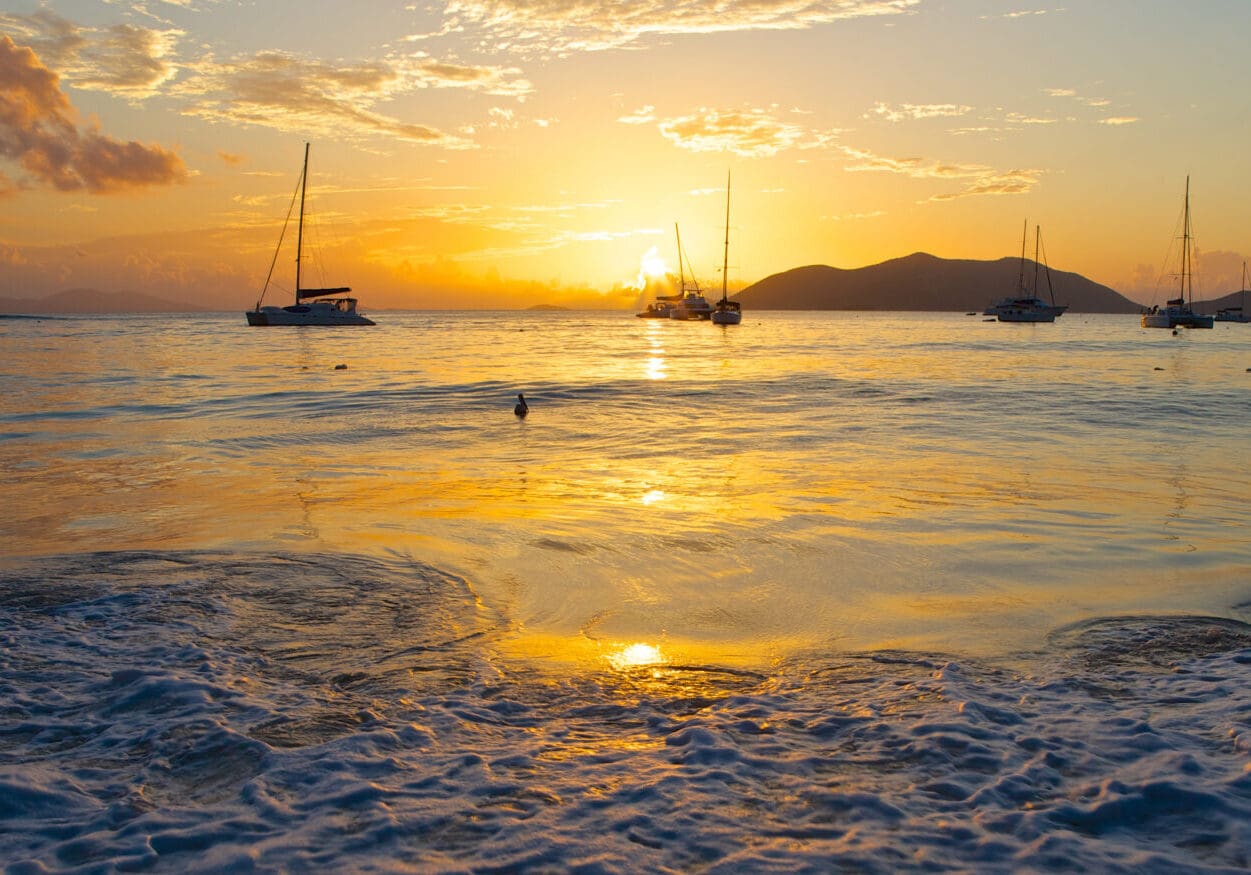 A sunset over the ocean with boats in it.