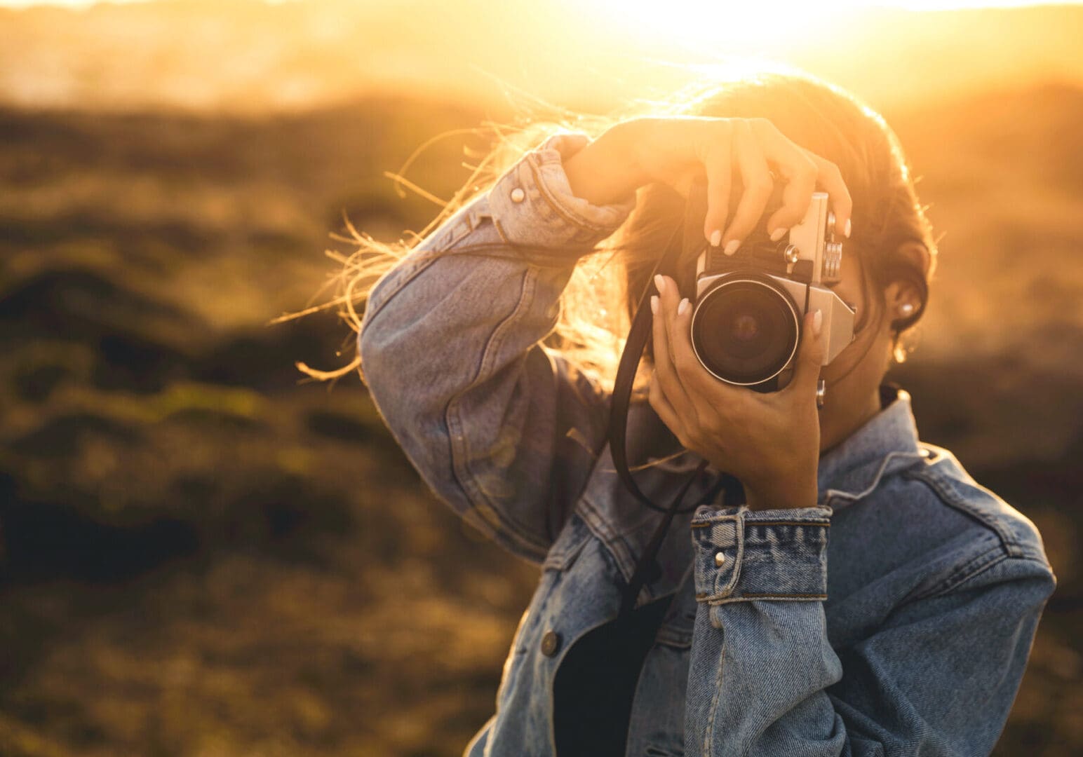 Beautiful woman taking picture outdoors with a analog camera