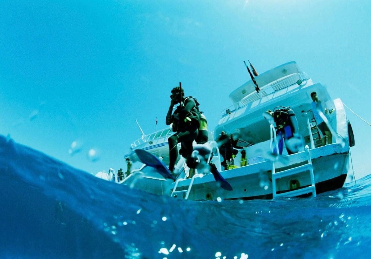 A group of scuba divers on the side of a boat.